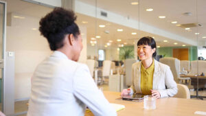 Female dentist having a conversation with another female while sitting at a table.