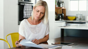 A woman in her 40s reviews her life insurance policy to avoid life insurance mistakes.