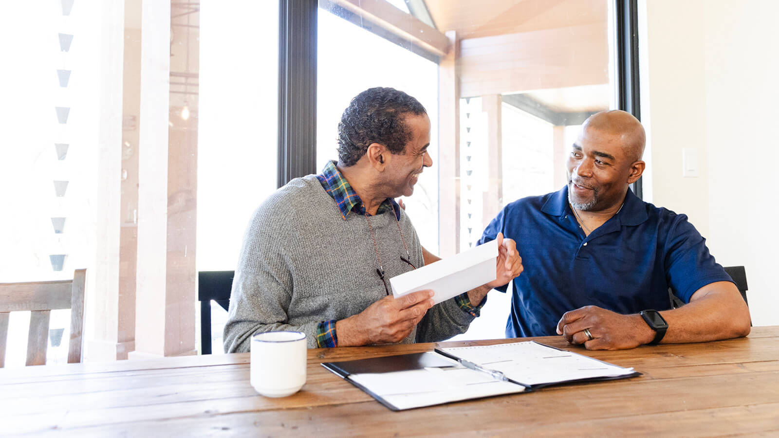 A son sits next to his father, proud to be a second-generation financial professional working alongside his father in their family’s financial practice.