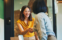 Two women smile and shake hands as they discuss their business partnership through a professional employer organization.