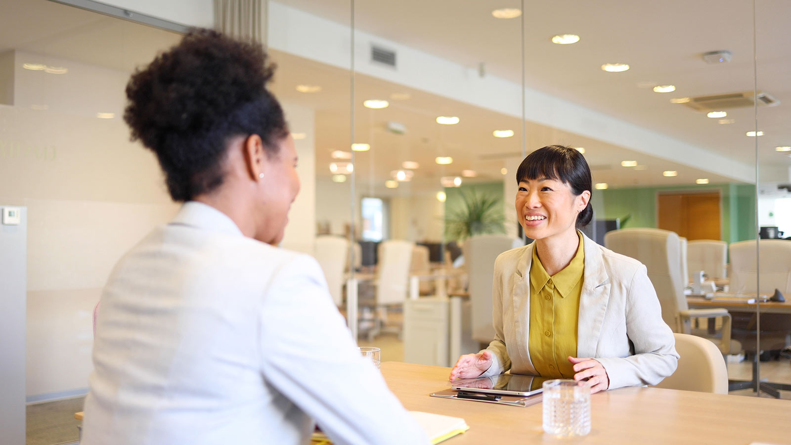 Female dentist having a conversation with another female while sitting at a table.