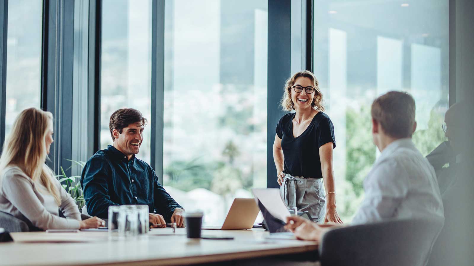 A CEO meets with some of her employees in a modern office space to explain how managed account programs will benefit their retirement plan employee benefit.