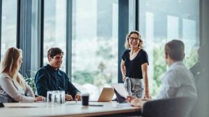 A CEO meets with some of her employees in a modern office space to explain how managed account programs will benefit their retirement plan employee benefit.