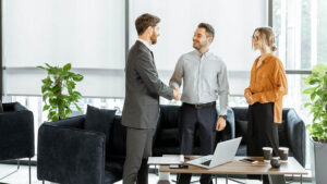 Business executives shake hands with a retirement plan professional to discuss private-label retirement plan solutions for their business.