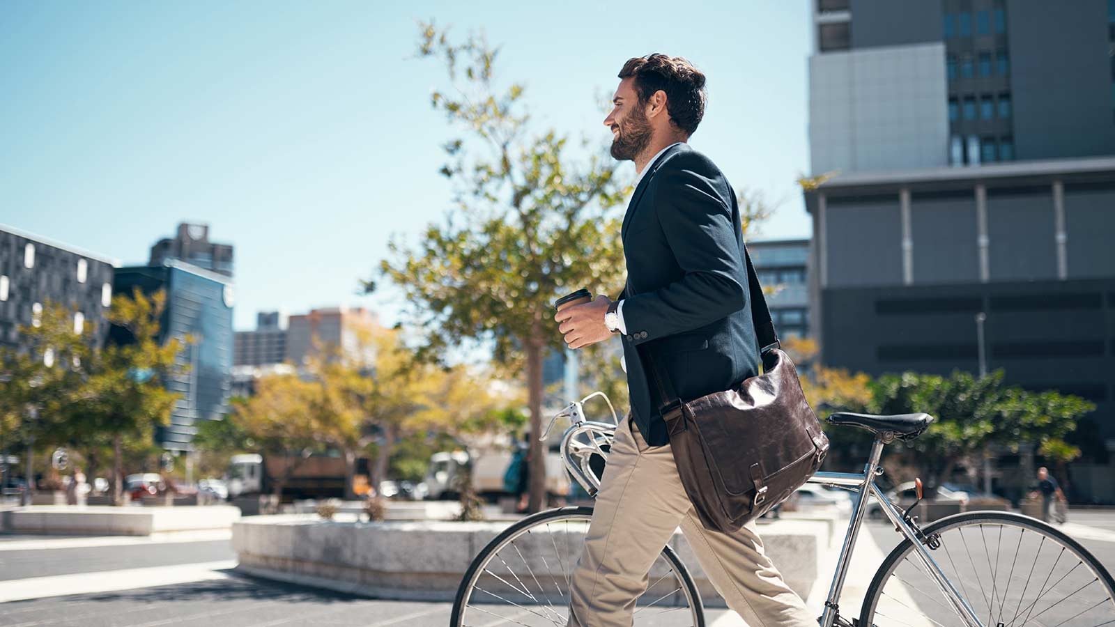 Man pushing his bike on a sidewalk in an urban area.