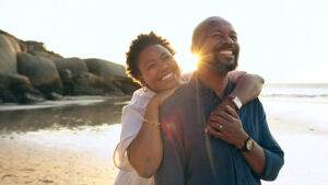 Happy male and female near body of water at sundown.