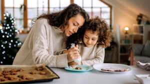 Mother and daughter baking and decorating cookies in the kitchen.