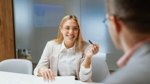 A woman in her late 20s meets with a financial professional for the first time. She’s prepared with her financial documents and a checklist with questions for the meeting.