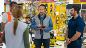 A business owner meets with his key employees in his hardware store to discuss sales strategies before the store opens.