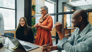 The CEO of a small company enjoys a laugh with some of her employees during a meeting to talk about employee engagement.