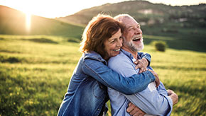 Elderly couple laughing, hugging and enjoying the outdoors.